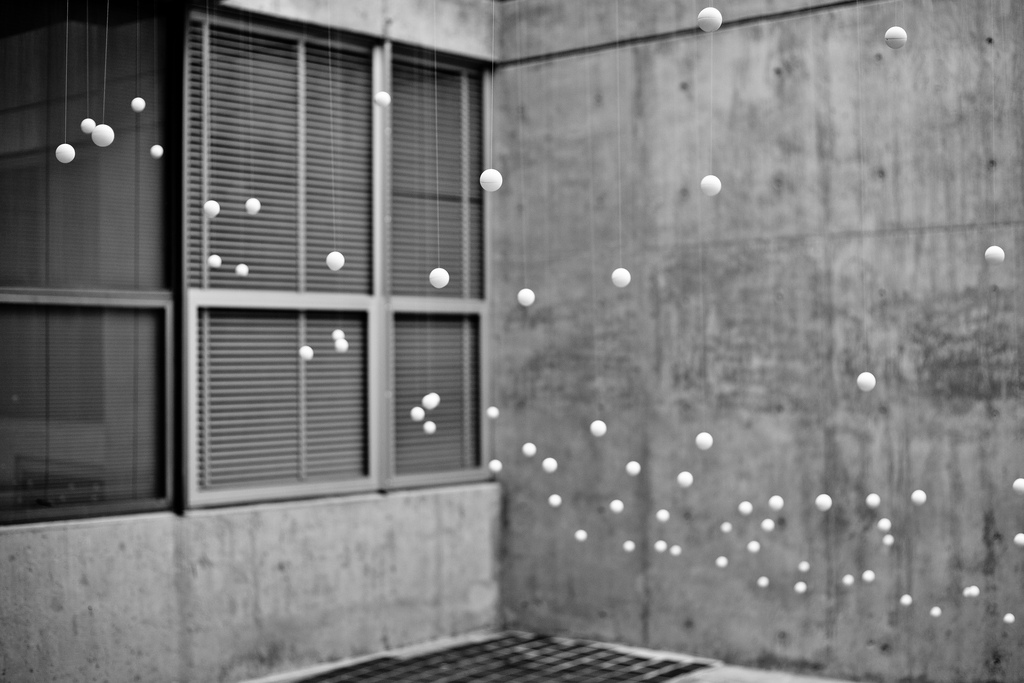balls hanging from a ceiling in front of a concrete wall