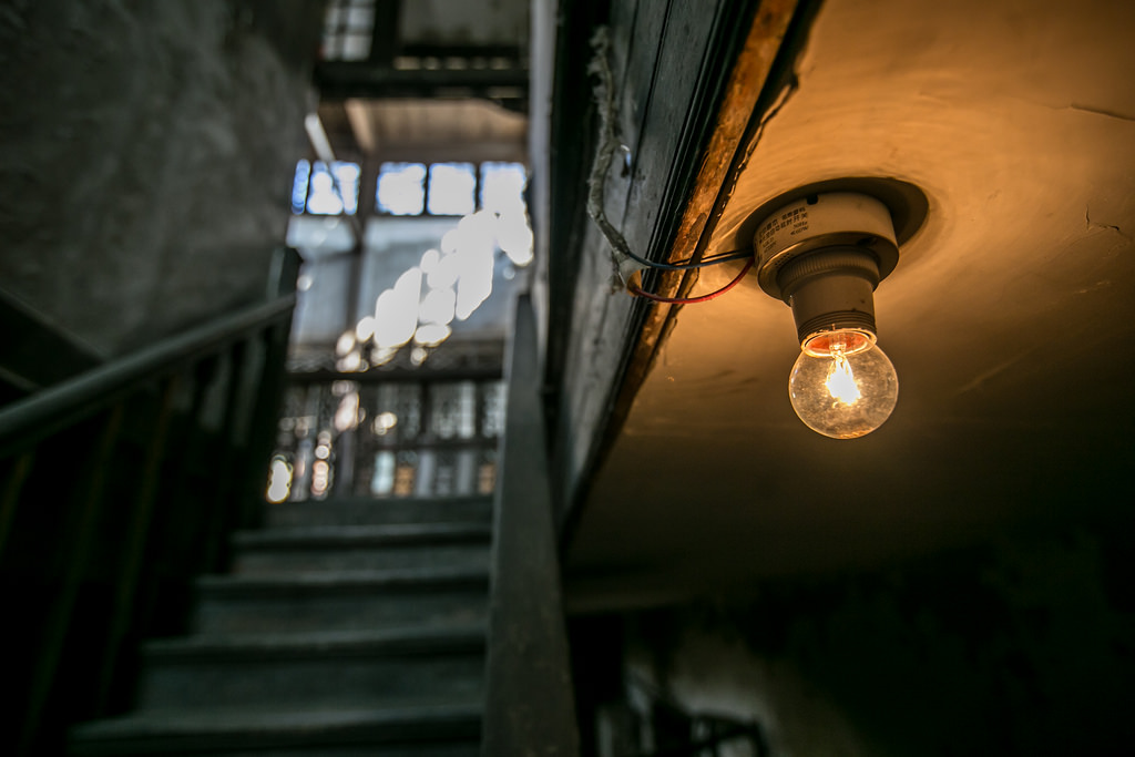 single lightbulb illuminating an alley with a staircase