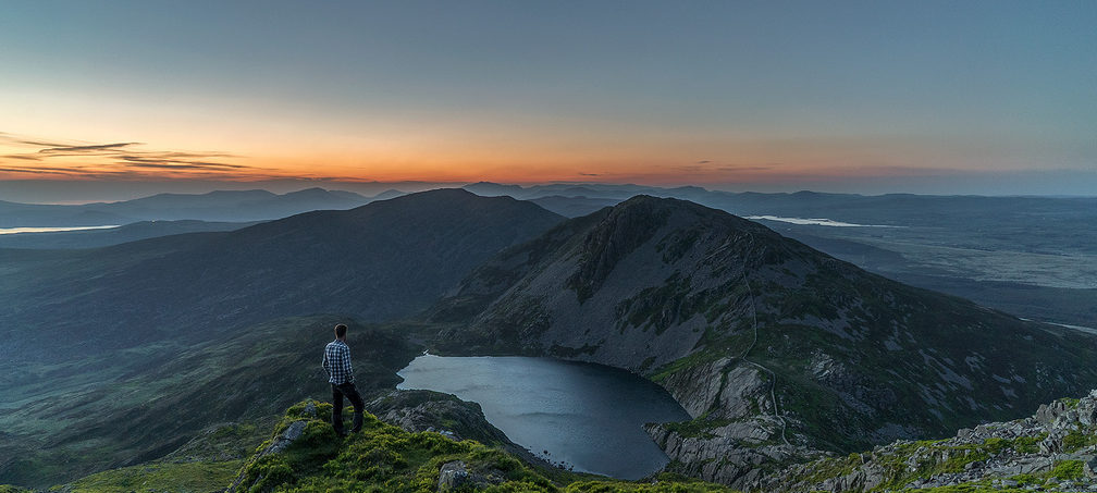 man standing on mountaintop, watching sunrise